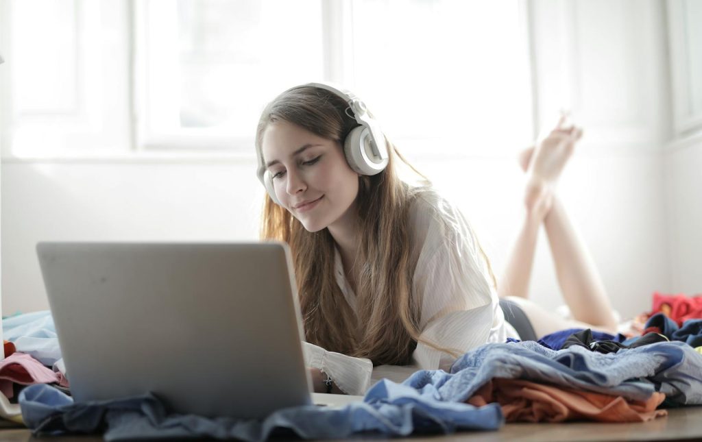 Femme avec casque écoutant de la musique devant un ordinateur portable