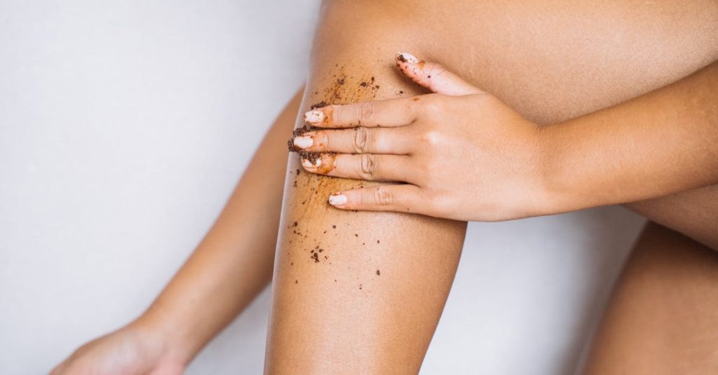 Femme appliquant un gommage sur sa jambe